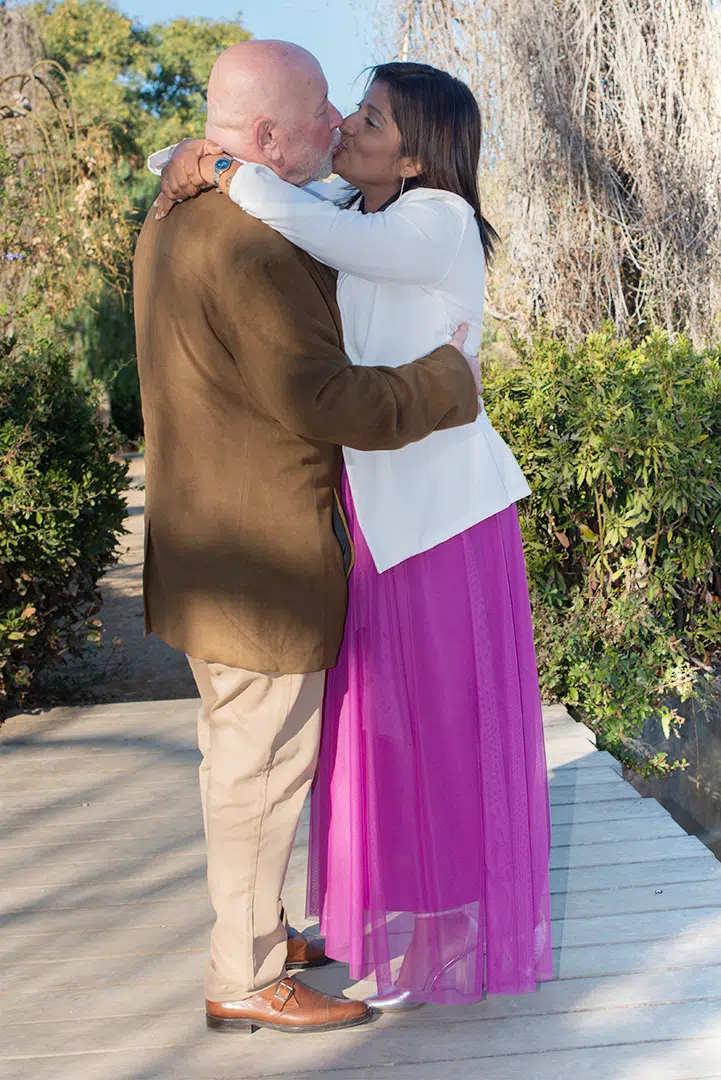 Los novios se besan con una sonrisa compartida, capturando la esencia de un amor auténtico y alegre.