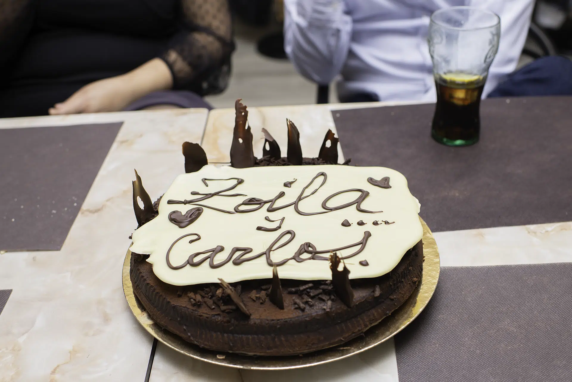 El pastel se presenta en primer plano, recordando que cada dulce capa es un capítulo de la historia que la pareja comienza a escribir juntos.